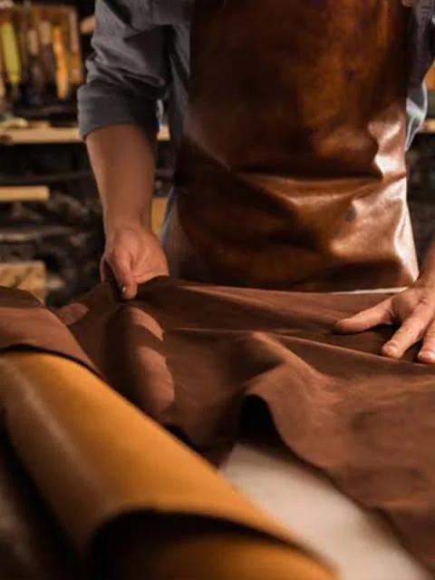 Craftsperson carefully handling and cutting leather in the workshop